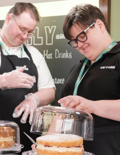 Two happy waiters preparing cake slices ready to serve