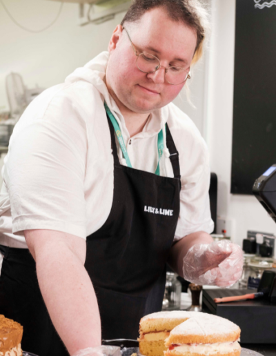 Young man preparing a slice of Victoria sponge cake