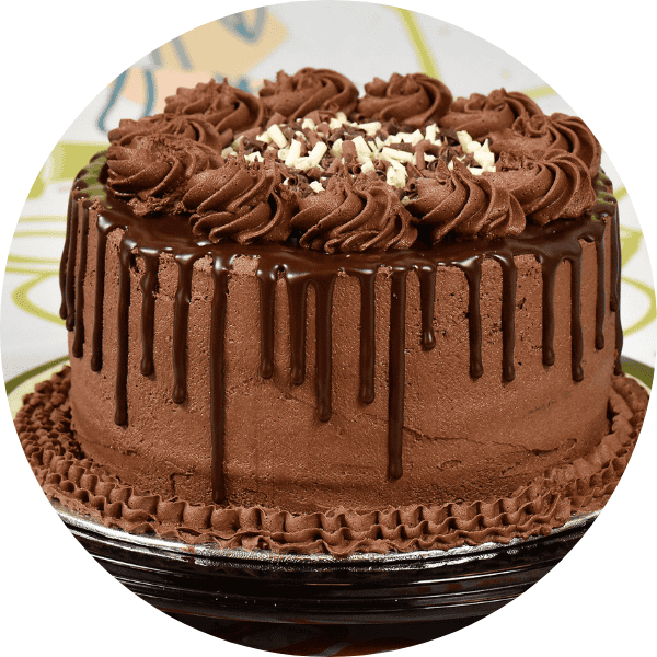 Chocolate cake decorated with swirls of chocolate icing on top and drips of chocolate round the side of the cake. 